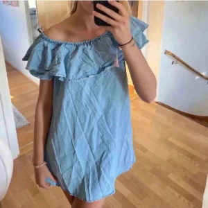 Zara Klänning - Volangklänning i blått mjukt jeans material! Kan användas offshoulder och mer uppdraget! Perfekt till sommaren! Använd ett fåtal gånger. Bild 1 och 3 lånade, skriv för fler bilder!