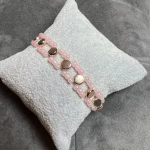 Egentillverkat armband i rosa och guld. Är gjort med gummitråd och är ca 15 cm långt.