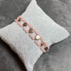 Pärlarmband  - Egentillverkat armband i rosa och guld. Är gjort med gummitråd och är ca 15 cm långt.