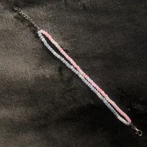Egentillverkat armband i två rader med rosa-vita och blå-vita pärlor och silvrigt spänne. Justerbar passform mellan 19-24 cm.