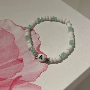 Hemmagjort armband - Säljer ett armband som jag har gjort själv. Nu kan jag inte veta hur stor sin armled är men kolla på bilderna!  Det är ett armband med tre vita sen två turkosa sen mellan två stjärnor är det ett A. 