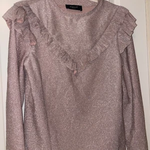 Glittrig långärmad tröja  - Ljusrosa glittrig långärmad. Använd 2/3 gånger. Mycket bra skick. Storlek XS. Super fin på fest. Från SisterS point. 