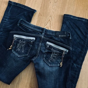 Lågmidjade bootcut jeans  - Lågmidjade mörkblåa bootcut jeans från Redial, snygga detaljer på baksidan, midjemått 40cm, innerben 83cm,