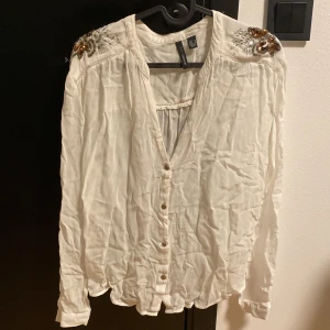 Blus - Vit blus med detaljer på axlarna, den är inte struken men går att stryka.