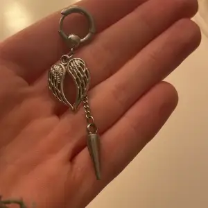Ett silvrigt silver smycke med en ring, vingar och en spets