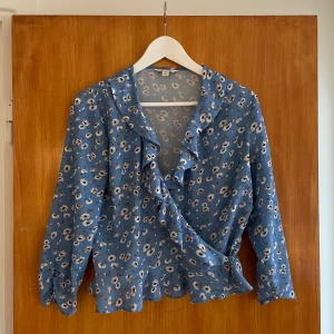 Blå blommig omlott-blus  - Blå blommig omlettblus.  Storlek 40, men passform mer som 36/38. 