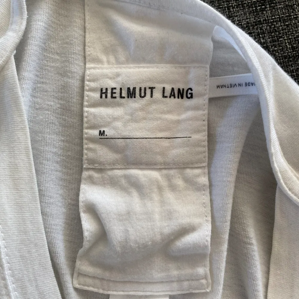 Storlek Small Helmut Lang ”PR Team” T-shirt som är i väldigt bra skick förutom 2 st små hål som är 1-2 mm stora (se bilder) men de syns knappt. Kostar över 1000 ny.. T-shirts.