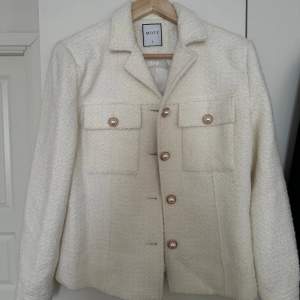 Oanvänd kappa i storlek Large. Jackan är i färgen vit och har glitterkorn. 