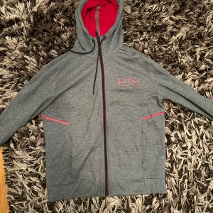 Hugo Boss zip hoodie - En Hugo Boss zip hoodie som inte finns att köpa tillgänglig längre, den är i mycket mycket bra skick förutom en liten detalj på repet på tröjan, man kan få bild på det i Dm men annars i topp skick, i storlek S är den! 