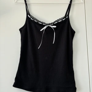 Svart linne med rosett - Jättefint linne med spets detaljer och en rosett från HM!🎀 Endast provad, etikett finns kvar. Finns även i vit, använd gärna köp nu 💕