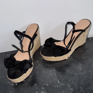 Klackskor med svarta rosetter - Supersnygga söta klackar / sandaletter med svarta rosetter, superfina men används inte längre. Använda fåtal ggr. Storlek 40 men kan passa 39 som jag har. 10cm höga. 