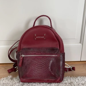 Röd mini ryggsäck  - En röd liten ryggsäck i fakeläder. Den är endast använd en gång. Säljer för 150kr exklusive frakt