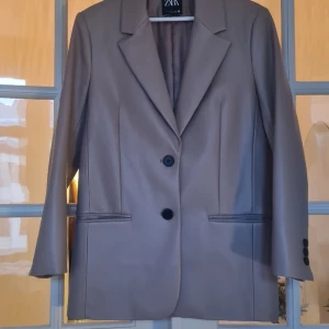 Beige läderkavaj - Oanvänd beige faux-leather kavaj med lätt rosa ton. 