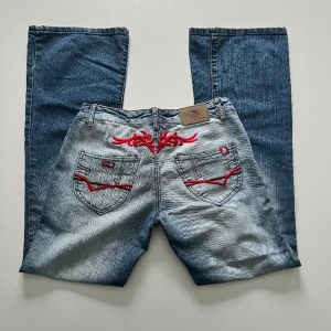 Lågmidjade jeans - Vintage lågmidjade bootcut jeans från Bagost Jeans med röda detaljer. Midjemått: 74 cm. Innerbenslängd: 79 cm. Strorlek W30 men passar mer W28-29. Jag är 176 cm 💓