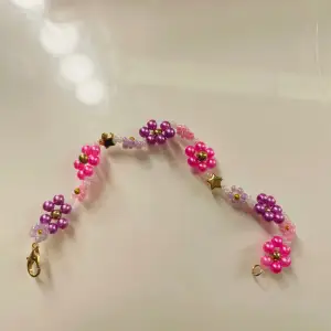 ett sååå sjukt fint och somrigt armband med rosa och lila blommor💜🩷