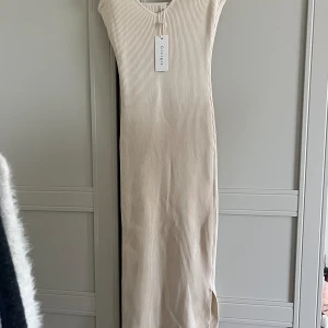 Klänning - Lång klänning med slits, storlek M/L men passar XS-M. Oanvänd med prislapp kvar. Den har en defekt som syns på sista bilden, annars nyskick