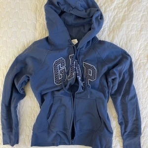 Blå hoodie från GAP - Mellanblå zip-hoodie från GAP. Köpt förra året och är i nyskick.