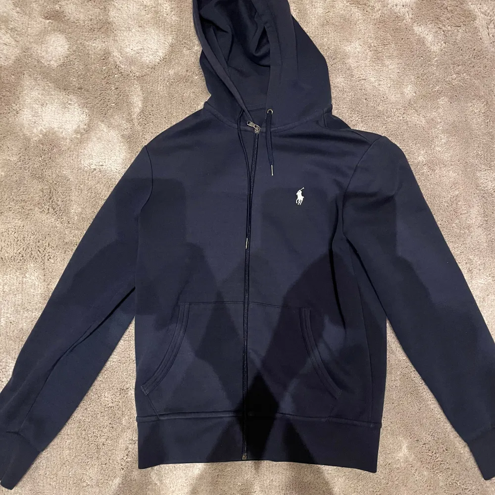 Snygg Ralph lauren zip hoodie köpt på nk i Göteborg. Hoodien är i storlek Xs. Den är använd sparsamt men inga defekter, därav skick 8/10. . Hoodies.