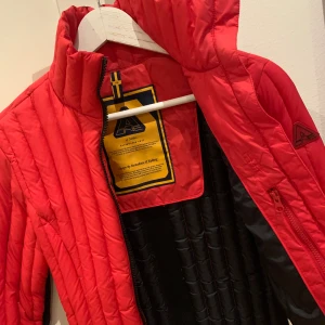 Dunjacka A-one - Super fin klarröd lättviktsjacka.  Märke A-one nypris 2500. Väger ingenting och är jättevarm. Sjukt snygg, ser lite retro ut med svart rand i bak.  väldigt tidlös o användbar, Funkar perfekt  som skidjacka.  Lite för liten för mig. Därav Nyskick.