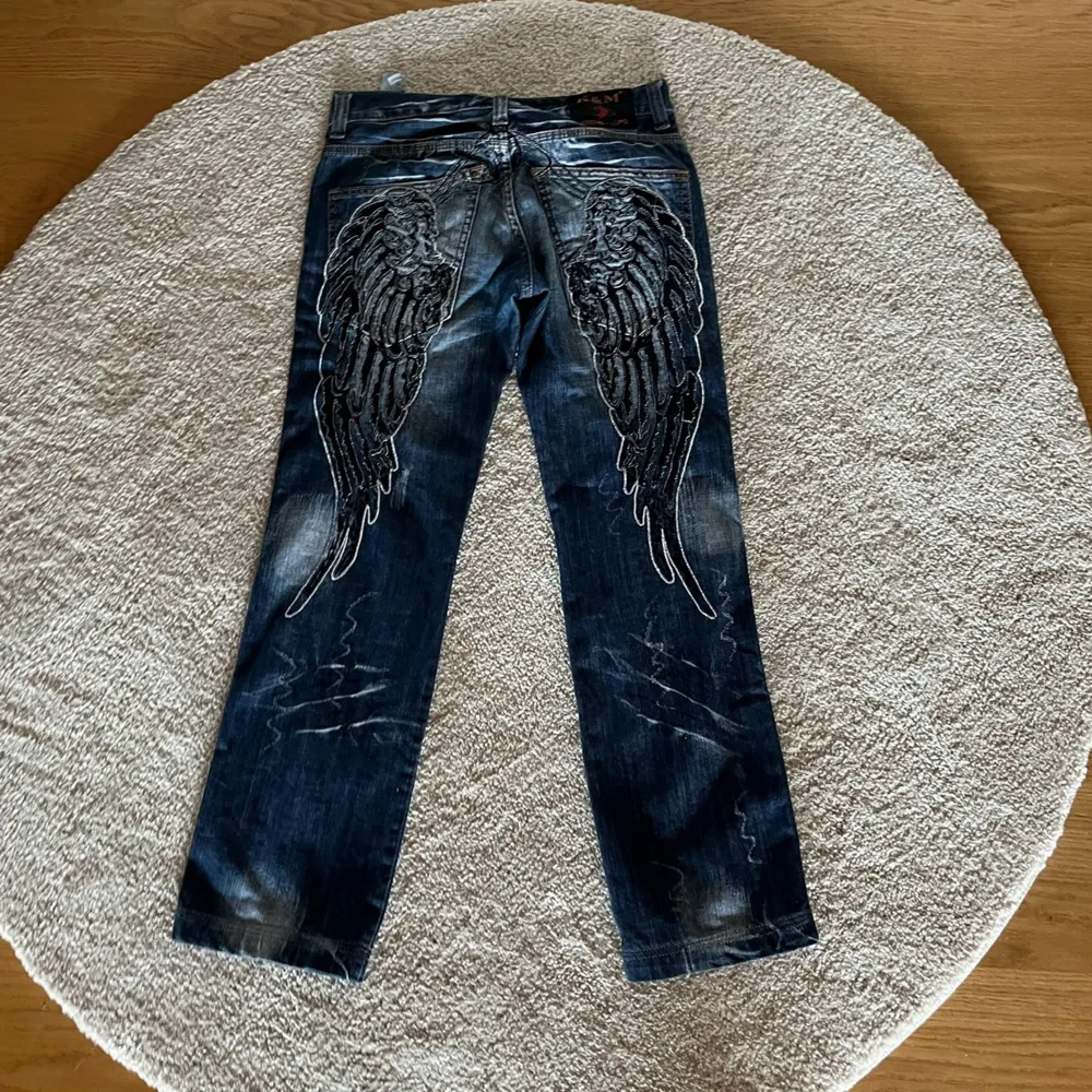 Super coola jeans med vingar på baksidan! Från komso lupo, super bra skick. midjemått: 38cm, innerbenslängd: 78cm, ytterbenslängd: 96cm. Jeans & Byxor.