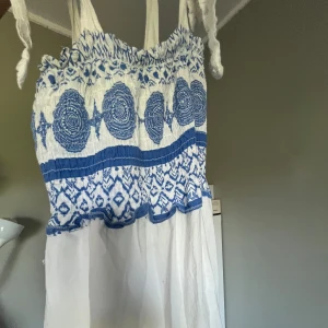 Vit och blå strandklänning - As fin strand klänning köpt på en okänd butik i st tropez! Knappt använd, det var svårt att ta bild på hela klänningen då den är lång men har iaf fått med alla delar av den🩵😅