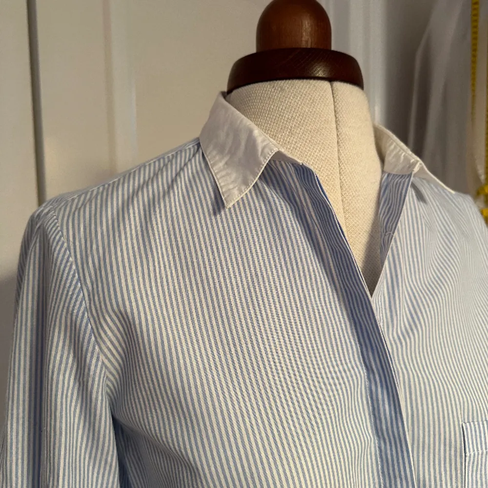 Ljusblå randig skjorta med vit krage. . Skjortor.