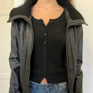 Vintage skinnjacka - Svart jacka i äkta skinn med lång krage, gott skick, lite sliten på lädret på sina ställen, men är säker att det kan fixas med läderbalsam. Säljer via köp nu. Står strl 38. Uppskattad storlek - XS el S.  Bröstmått tvärsöver: 45 cm Längd: 49 cm