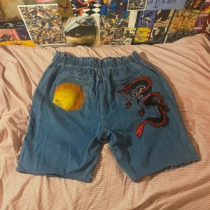 Väldigt baggy jorts custom design - Stora jorts. Nedklippta byxor med stryk patch och sprejat/målat på backsidan. Midjan är elastisk men är ungefär 38 Måtten är midja 48, längd 62 och ben öppningar 30 