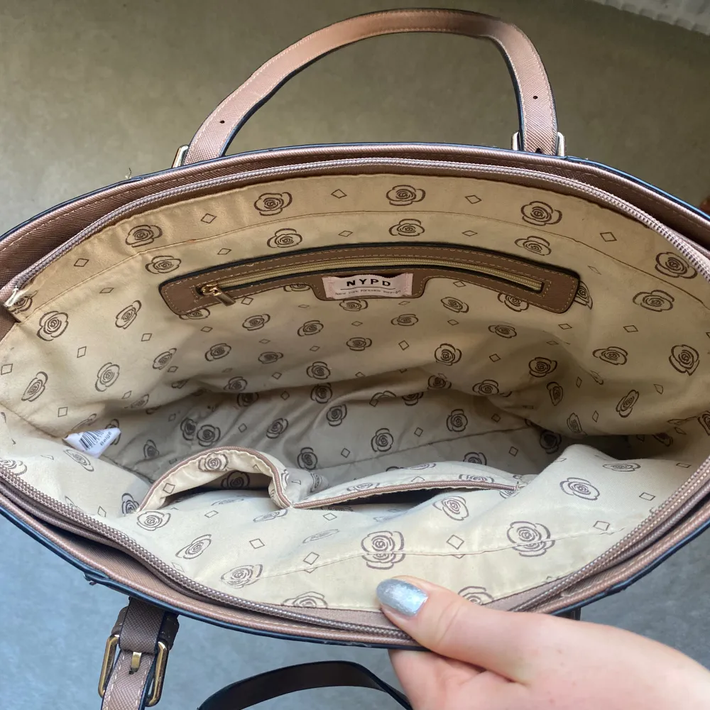 Brun handväska med dragkedjeficka och fack. Använd men i fint skick från new york portable design. Väskor.