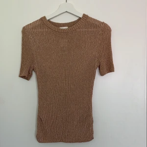 Glansig stickad t shirt  - Fin stickad topp som är glansig av sig. Tröjan är beige/ rosa och storlek S.
