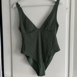 Grön baddräkt  - Grön baddräkt från hm. Fint skick! Uringad fram och låg rygg bak. Se tredje bilden för material och färg i dagsljus. 