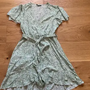 En grönblommig klänning med v-ringning från Shein i storlek M. Jag säljer eftersom att jag inte passar i den.