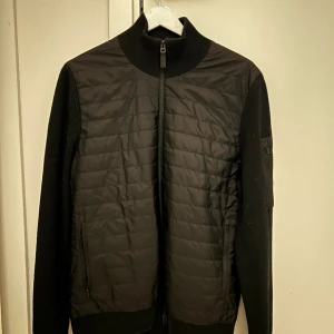 J.Lindeberg cardigan - Säljer denna nyinköpta J.Lindeberg hybridjacka i storlek medium! Från senaste höstkollektionen så den är knappt hunnit bli använd!  Ny pris 3200 Rea pris just nu 1600 Fler bilder finns, bara att höra av sig! 