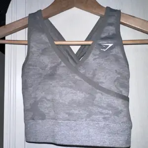 Tag size S, but RUNS SMALL!!!! I wrote XS, but the tag is S. Please be very aware of this sizing. Grey sports bra with back cut outs and pad inserts. Logo print slightly cracked. Gently used condition with some fuzz. 