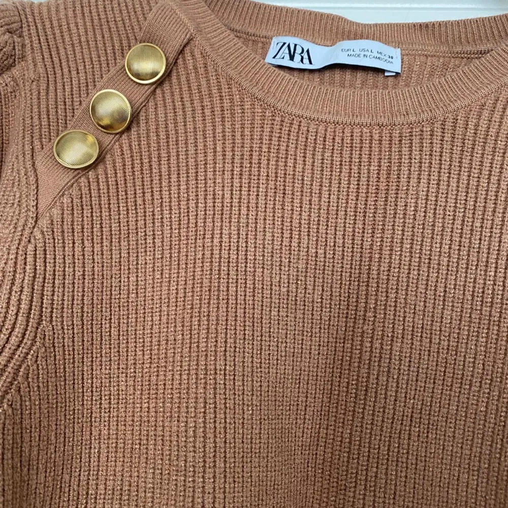 Jättefin beige tröja från Zara med guldiga knappar.  Tröjan är i fint skick, använd Max 2-3 gånger.  Tröjan är I storlek L men liten i storleken så skulle säga den är som M.. Tröjor & Koftor.