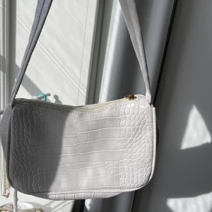 Vit liten väska - Söt liten axelväska i bra skick. Saknas en flärp till dragkedjan men det går att sätta dit vad som helst