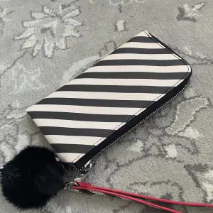 Plånbok med zebra mönster röd i insidan med en svart fluffboll som hänger på utsidan som dekoration 