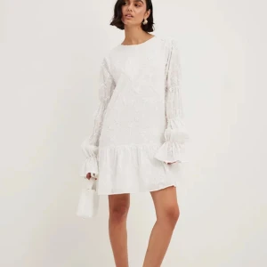 Klänning från nakd  - Student klänning med fin blomsterbrådyr. En lös modell med en öppen rygg! Långärmad puffärm! Endast använd en gång. Ny pris 699