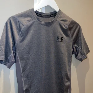 Under armour compression tshirt  - Under armour compression tshirt I mörkt grå  Storlek M  Jätte bra skick har endast använt ett par gånger 