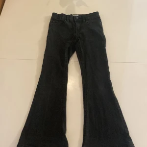 Svarta jeans storlek 134/140 - Ett par bootcut jeans i färgen svart. Har använt dom ganska många gånger. Dom har tappat lite färg på knappen men inget man tänker på.