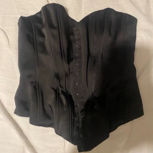 Svart korsett  - Säljer denna korsett då jag aldrig använt den. Sista bilden är hur den sitter på, det är samma korsett fast i vit färg 
