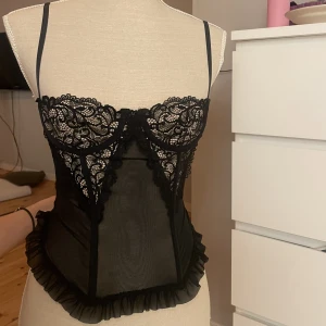 Korsett - Extremt fin korsett/ bralette topp m balconette- stil över bysten. Håller i den på dockan då den var för liten. Dragkedja där bak men har ett stretchigt material. Mått i midjan tvärs över är ca 28 cm, men skulle säga att den passar 26 - 34 cm. Frågor- Dm 