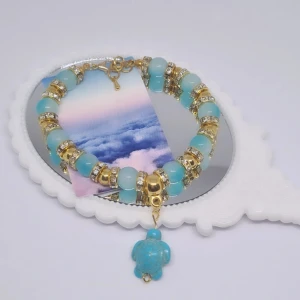 Lilla sköldpaddan armband - Tvåfärgade glaspärlor som är blå-ljusblå/vita pärlor med guld detaljer, guldiga mellan pärlor med fejkade diamanter. Armbandet är cirka 16 cm och är justerbart. Armbandet kan göras om efter önskad storlek. 