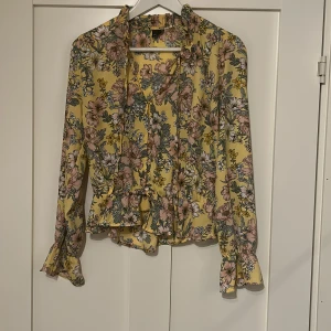 Blus - Blus med blommönster. Knappar och snörning framtill. Nyskick