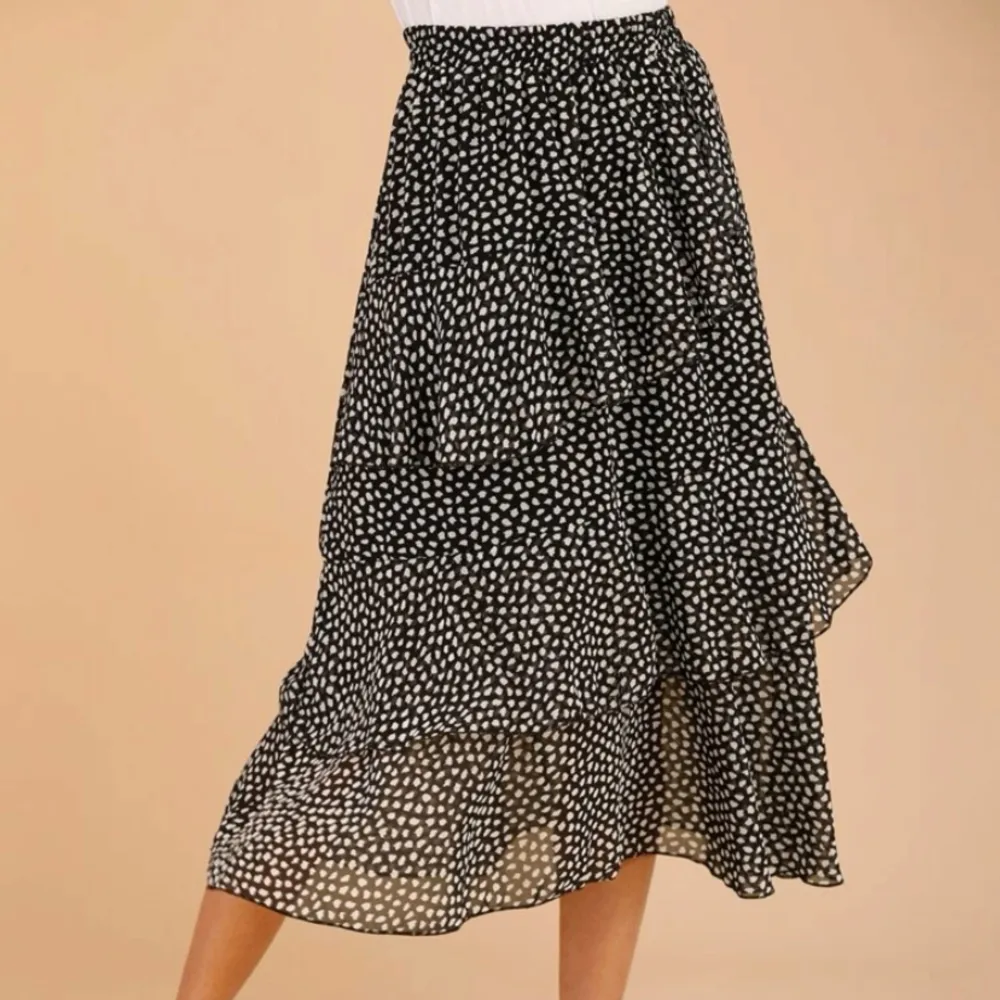 En lång kjol i bra kvalitet och material. Svart och vitprickig design med volanger. . Kjolar.
