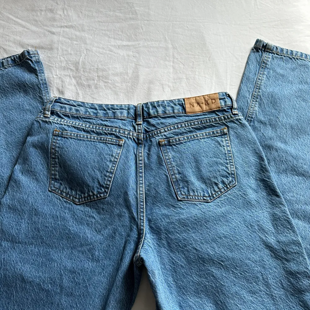Blåa low waist byxor från NA-KD. Storleken 38!  Väldigt bra skick då den har använts 2 gånger. Säljer de på grund av att de är ganska korta på mig. Jag är 176 cm och byxorna slutar vid ankeln på mig. Jätte fina byxor! Ordinarie priset var 699 kr. . Jeans & Byxor.