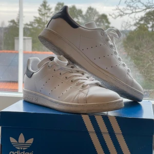 Stan Smith - Säljer mina adidas Stan Smith skor, på grund av att de hann bli för små. De är endast använda utomhus en gång, vilket bara syns under sulan. Vita med mörkblå detaljer. Strl 38 2/3. Skriv för fler bilder💗