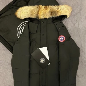 Canada goose jacka  - Säljer en Canada Goose jacka i färgen grå/svart, storlek L. Helt ny, bra kvalitet.