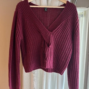 Mysig stickad tröja - En mysig vinröd stickad tröja med flätning framtill