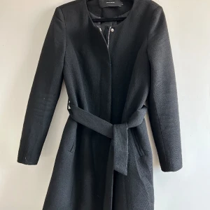 Svart kappa  - Svart kappa från Vero Moda. Både dragkedja, knappar och knytning i midjan. Använd men i fint skick 